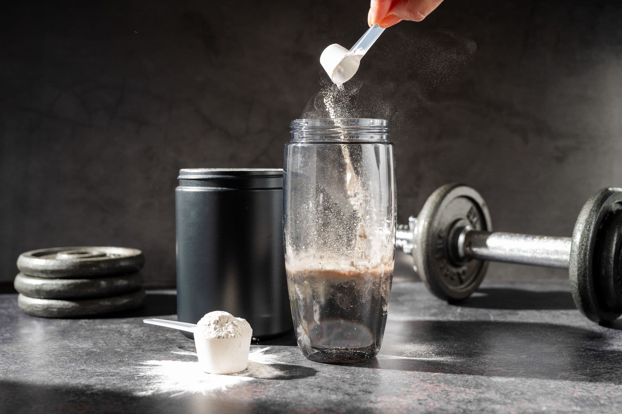 Powder supplement being scooped into shaker bottle